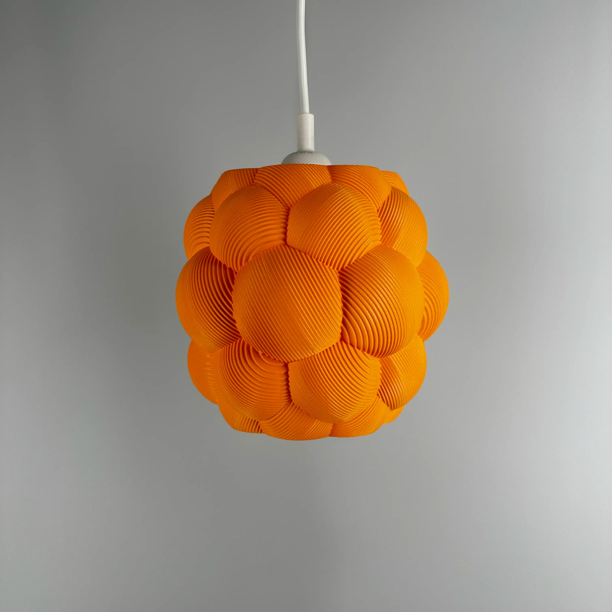 3D printed Apo Malli lampshade in modern design in orange biodegradable material.